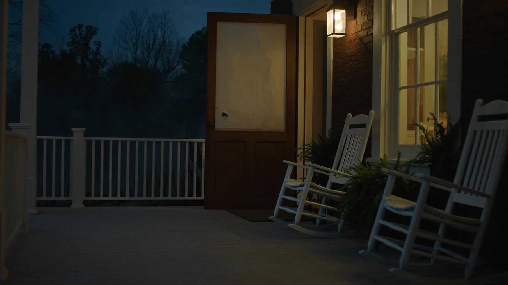 A Southern front porch at dusk with warm light glowing through the screen door
